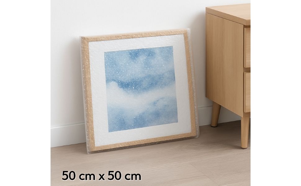 Cadre protégé dans une pochette bulle 50x50 cm, posé sur une table dans un intérieur lumineux